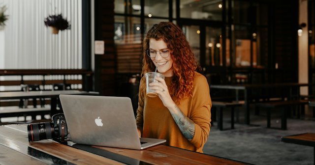 Mujer revisando datos en su portátil con un café