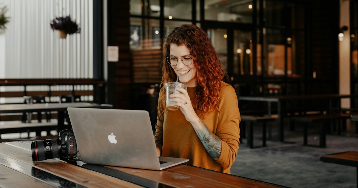 Mujer revisando datos en su portátil con un café