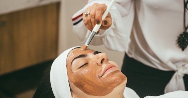 Esteticista aplicando una mascarilla facial a una clienta