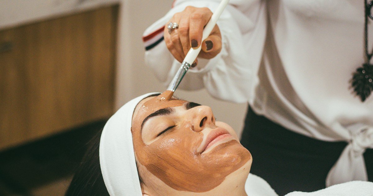 Esteticista aplicando una mascarilla facial a una clienta