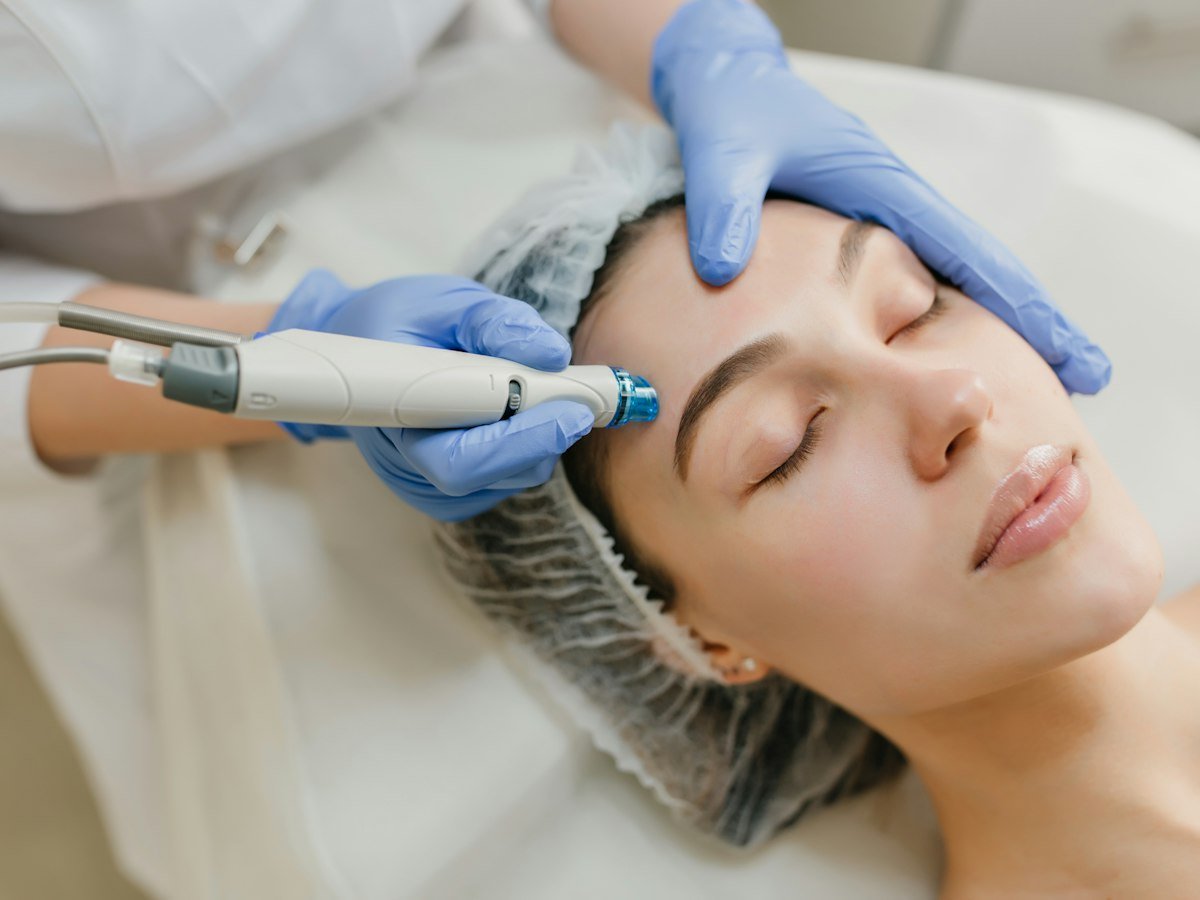 Esteticista con guantes haciendo un tratamiento facial a una clienta en cabina